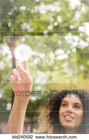 Stock Image - Mixed Race woman pointing to virtual screen outdoors. Fotosearch