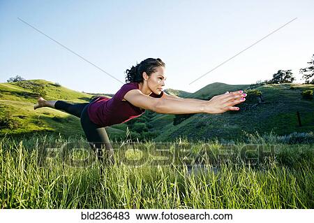 Stock Image - Mixed Race woman practicing yoga on hill. Fotosearch