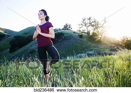 Stock Photograph - Mixed Race woman practicing yoga on hill. Fotosearch