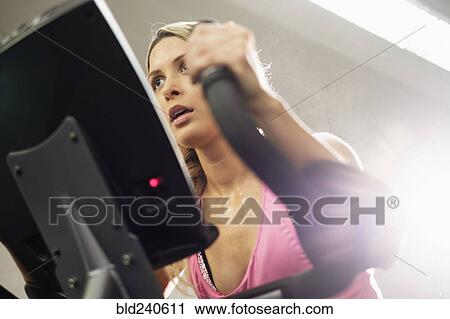 Mixed Race woman riding stationary bicycle View Large Photo Image Stock Image - Mixed Race woman riding stationary bicycle. Fotosearch