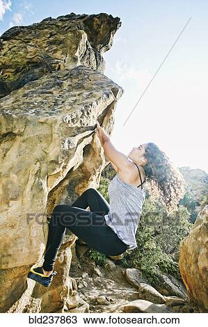 Stock Image - Mixed Race woman rock climbing. Fotosearch