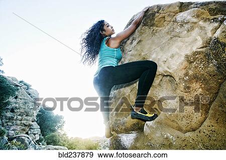 Stock Photo - Mixed Race woman rock climbing. Fotosearch
