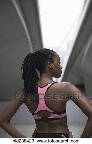 Stock Image - Mixed Race woman running standing under urban bridge. Fotosearch