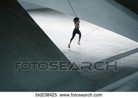 Mixed Race woman running under urban structure View Large Photo Image Stock Photography - Mixed Race woman running under urban structure. Fotosearch