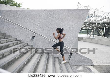 Stock Photograph - Mixed Race woman running up urban staircase. Fotosearch