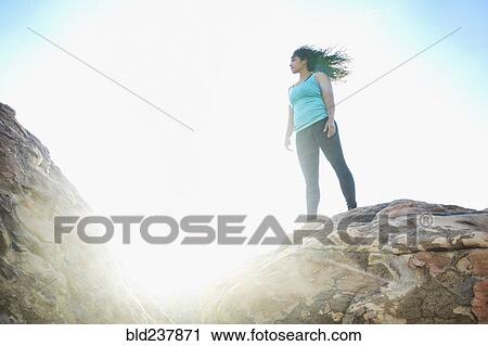 Stock Image - Mixed Race woman standing on rock. Fotosearch