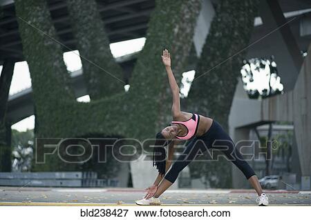 Mixed Race woman stretching under bridge View Large Photo Image Stock Photo - Mixed Race woman stretching under bridge. Fotosearch