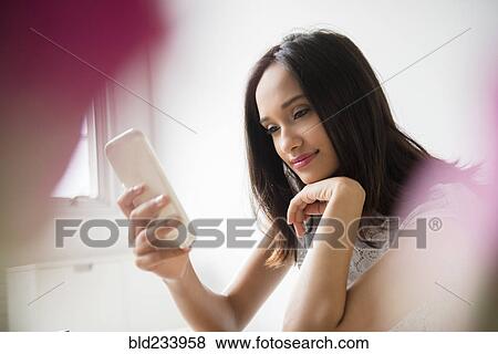 Stock Photo - Mixed Race woman texting on cell phone. Fotosearch