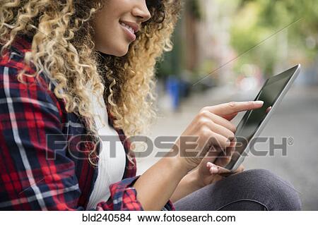 Picture - Mixed Race woman using digital tablet in city. Fotosearch