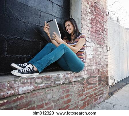 Mixed race woman using digital tablet outdoors View Large Photo Image Stock Image - Mixed race woman using digital tablet outdoors. Fotosearch