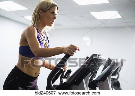 Stock Photo - Mixed Race woman using elliptical machine. Fotosearch
