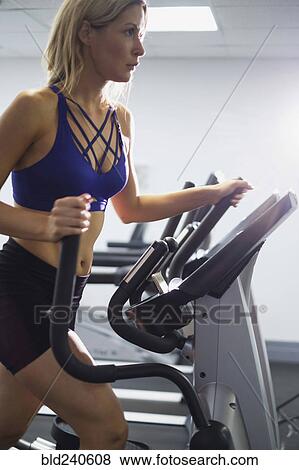 Mixed Race woman using elliptical machine View Large Photo Image Stock Photo - Mixed Race woman using elliptical machine. Fotosearch