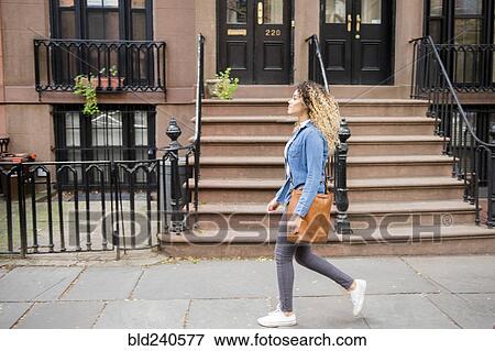 Stock Photo - Mixed Race woman walking on city sidewalk. Fotosearch
