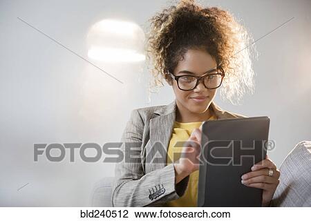 Mixed Race woman wearing eyeglasses using digital tablet View Large Photo Image Stock Image - Mixed Race woman wearing eyeglasses using digital tablet. Fotosearch