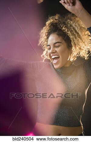 Picture - Mixed Race woman wearing sweater dancing. Fotosearch