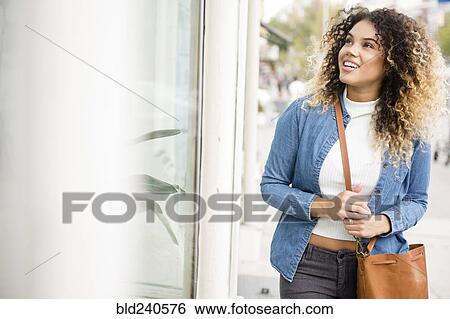 Stock Photograph - Mixed Race woman window shopping. Fotosearch