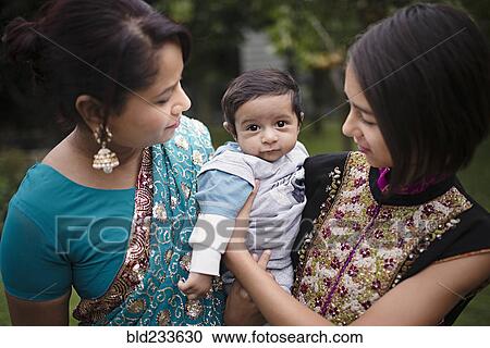 Stock Image - Mother and daughter admiring baby boy. Fotosearch