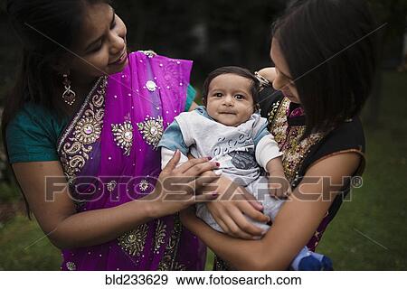 Stock Photo - Mother and daughter admiring baby boy. Fotosearch