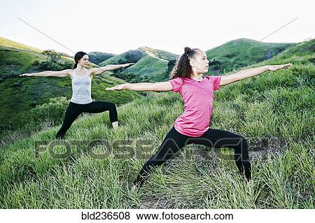 Stock Photo - Mother and daughter practicing yoga on hill. Fotosearch