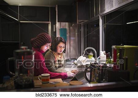 Mother and daughter using digital tablet in kitchen at night View Large Photo Image Stock Photography - Mother and daughter using digital tablet in kitchen at night. Fotosearch