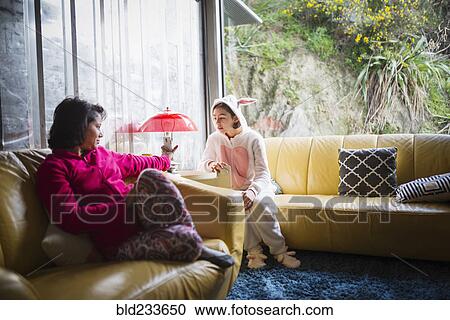 Stock Image - Mother showing cell phone to daughter wearing rabbit costume. Fotosearch