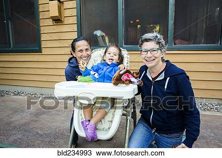Mothers posing with daughter in high chair View Large Photo Image Stock Image - Mothers posing with daughter in high chair. Fotosearch