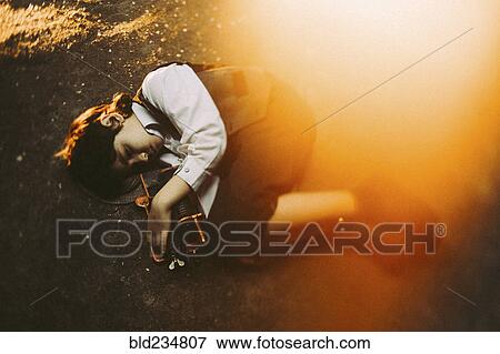 Stock Photo - Old-fashioned Caucasian boy laying in street holding machinery. Fotosearch