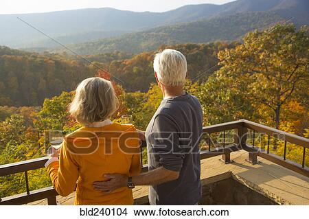 Picture - Older Caucasian couple enjoying wine and scenic view. Fotosearch