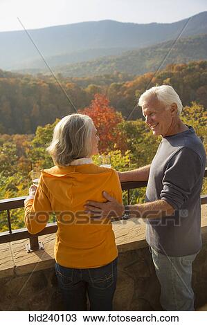 Stock Image - Older Caucasian couple enjoying wine and scenic view. Fotosearch