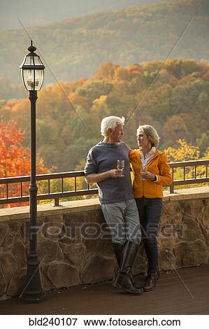 Stock Photo - Older Caucasian couple enjoying wine and scenic view. Fotosearch