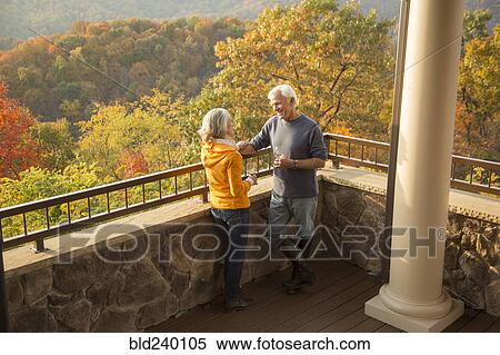Stock Photography - Older Caucasian couple enjoying wine and scenic view. Fotosearch