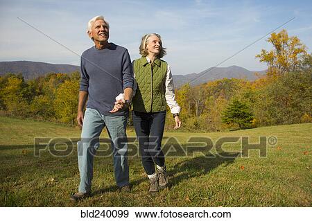 Older Caucasian couple walking in field View Large Photo Image Stock Photo - Older Caucasian couple walking in field. Fotosearch