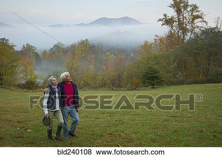 Older Caucasian couple walking in field View Large Photo Image Stock Photo - Older Caucasian couple walking in field. Fotosearch