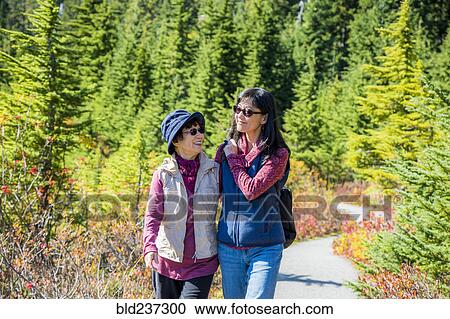 Stock Image - Older Japanese mother and daughter walking on nature path. Fotosearch