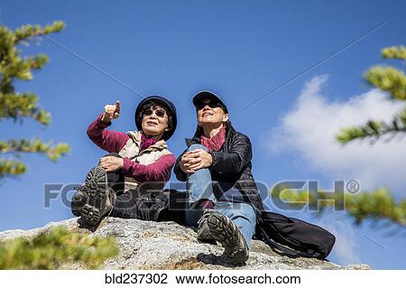 Stock Image - Older Japanese mother and daughter sitting on rock. Fotosearch