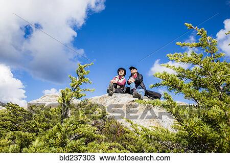 Stock Image - Older Japanese mother and daughter sitting on rock. Fotosearch