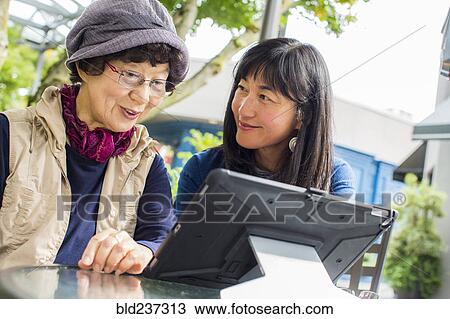 Older Japanese mother and daughter using digital tablet View Large Photo Image Stock Image - Older Japanese mother and daughter using digital tablet. Fotosearch
