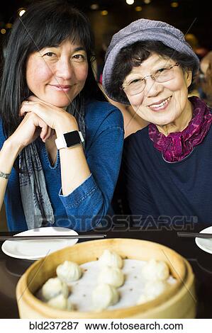 Stock Photo - Older Japanese mother and daughter smiling in restaurant. Fotosearch