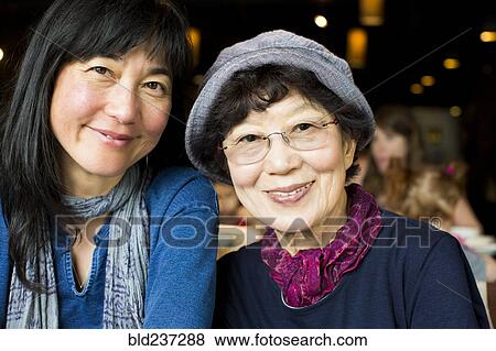 Stock Photo - Older Japanese mother and daughter smiling in restaurant. Fotosearch