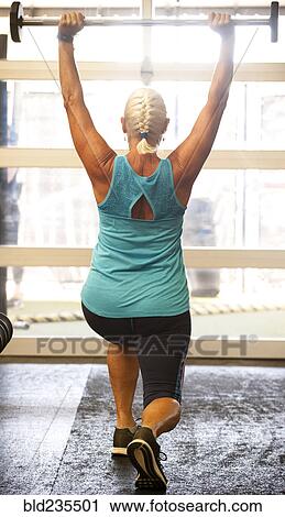 Older woman lifting barbell in gymnasium View Large Photo Image Stock Image - Older woman lifting barbell in gymnasium. Fotosearch
