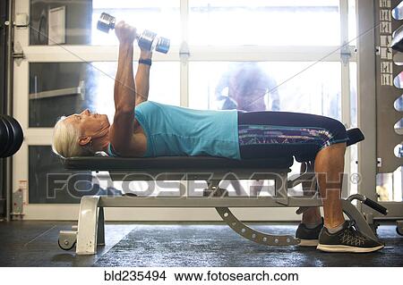 Older woman lifting dumbbells in gymnasium View Large Photo Image Picture - Older woman lifting dumbbells in gymnasium. Fotosearch