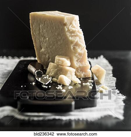 Stock Image - Parmesan cheese crumbles on cutting board. Fotosearch