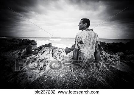 Pensive Caucasian man sitting on rocks at ocean View Large Photo Image Stock Image - Pensive Caucasian man sitting on rocks at ocean. Fotosearch