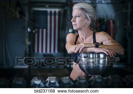 Stock Photo - Pensive Caucasian woman leaning on bowl in gymnasium. Fotosearch