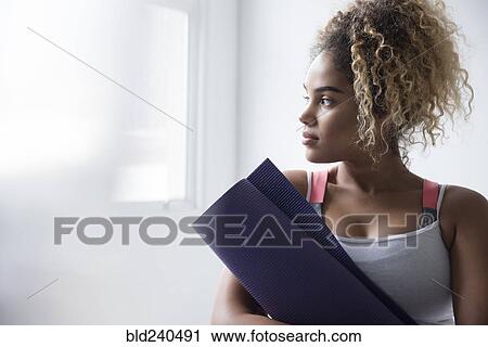 Pensive Mixed Race woman holding rolled up exercise mat View Large Photo Image Stock Image - Pensive Mixed Race woman holding rolled up exercise mat. Fotosearch