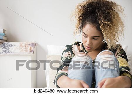 Stock Image - Pensive Mixed Race woman sitting on bed . Fotosearch