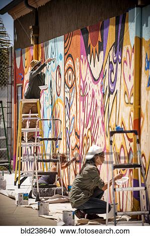 Stock Image - People painting mural on wall. Fotosearch