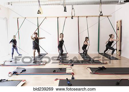 Stock Photo - People pushing on resistance bands in gymnasium. Fotosearch