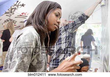 Stock Image - People tagging walls with graffiti. Fotosearch
