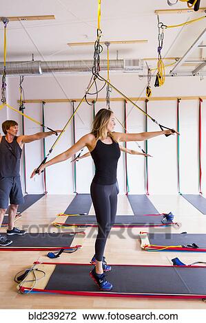 Stock Image - People using resistance bands in gymnasium. Fotosearch